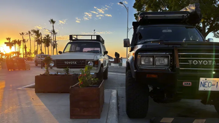 Experience adventure with an RV rental alternative: two rugged Toyota Land Cruisers parked by the water at sunset, equipped for overland journeys.. Toyota LandCruiser HJ61 VX 1989