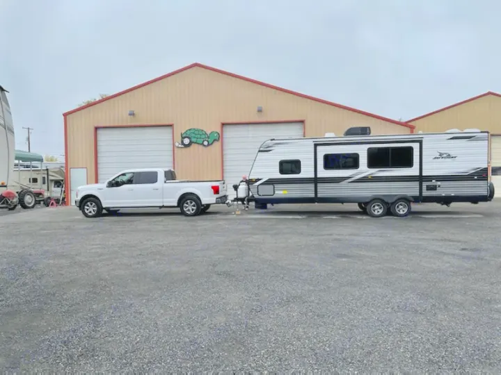 A white pickup truck is shown towing a Jay Flight travel trailer, perfect for RV rental.. Jayco JayFlight 267BHSW 2022