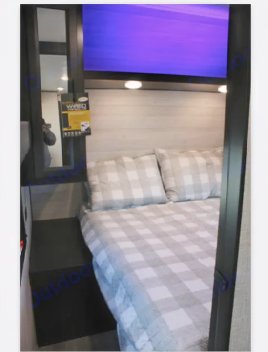 Cozy RV bedroom features gray checkered bedding, wood headboard, and purple-lit screen. Perfect for your RV rental trip.. Jayco JayFlight 267BHSW 2022