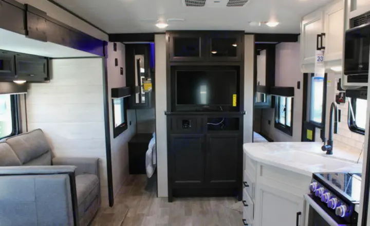 Spacious RV rental interior, showing a living area with sofa, entertainment center, and a modern kitchen on the right.. Jayco JayFlight 267BHSW 2022