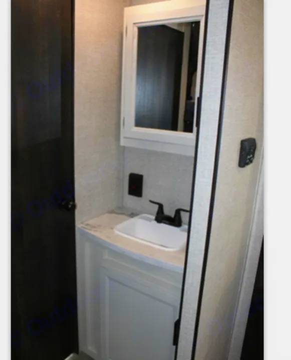 RV rental bathroom featuring a compact vanity, white sink, black faucet, and mirrored medicine cabinet.. Jayco JayFlight 267BHSW 2022