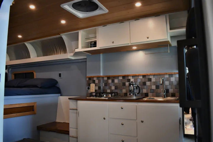 Cozy RV rental interior with compact kitchen, comfortable bed, and ample storage for your adventures.. Ram Other 2021