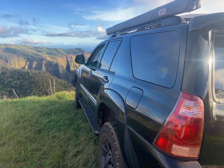 Black adventure SUV with awning at scenic cliff overlook. Ideal for a rugged RV rental experience.. Toyota 4runner 2003