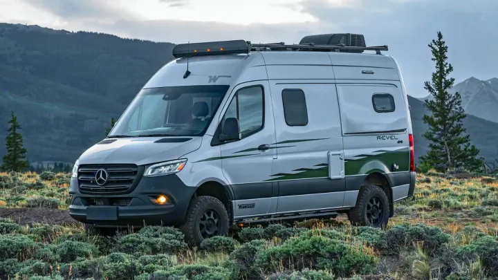 Explore with an RV rental: a silver Winnebago Revel 4x4 camper van in a rugged mountain landscape.. Winnebago Revel 2022