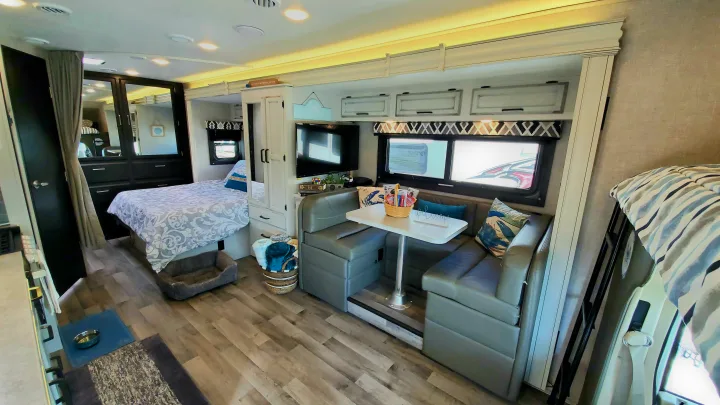 Spacious and modern RV rental interior with a bedroom, dinette, and living area, perfect for a cozy getaway. Pet-friendly!. Jayco Redhawk 2022
