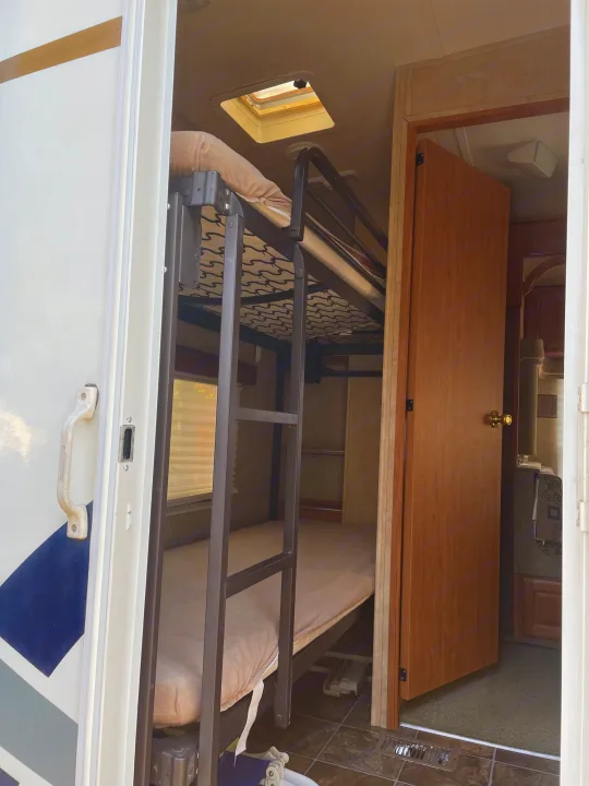 Explore this RV rental's interior featuring convenient bunk beds and an open door to more living space. Ideal for family trips.. Forest River Wildcat 2008