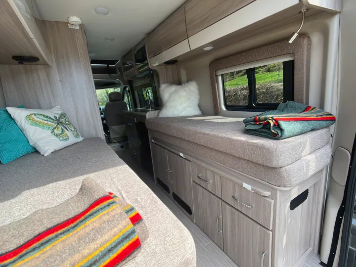 Spacious RV rental interior featuring comfortable seating/sleeping areas, a compact kitchen, and ample storage for travel.. Dodge Ram Thor Thor 2022