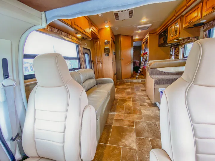 Spacious rv rental interior: cockpit seats, living area with sofa, kitchen, dinette, and rear bunk beds.. Thor Chateau 2016