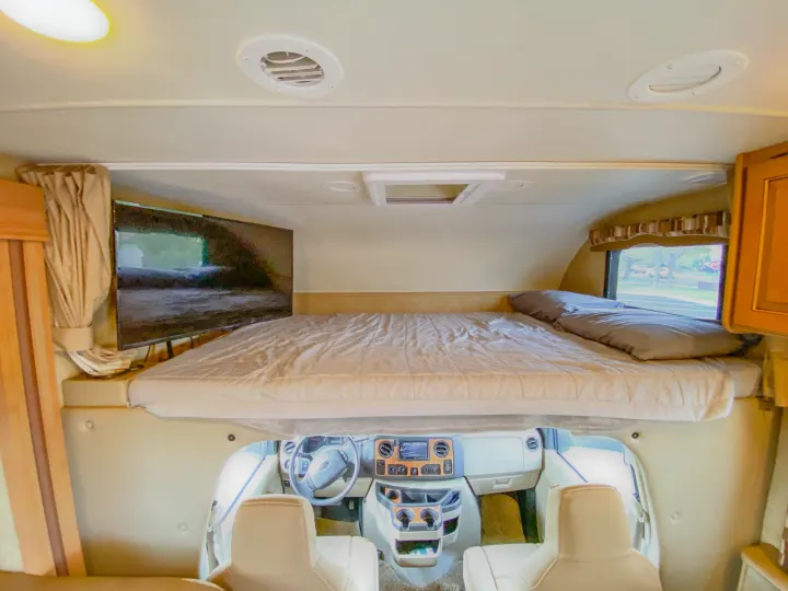 Explore this RV rental's cozy cab-over bunk bed with TV, overlooking the modern driver's cockpit.. Thor Chateau 2016