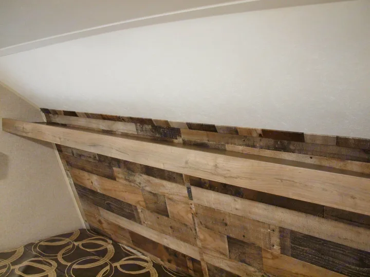 Comfortable RV rental interior: featuring a unique wood plank headboard with an integrated shelf for cozy stays.. Dutchmen Aspen Trail LE 1950BH 2020