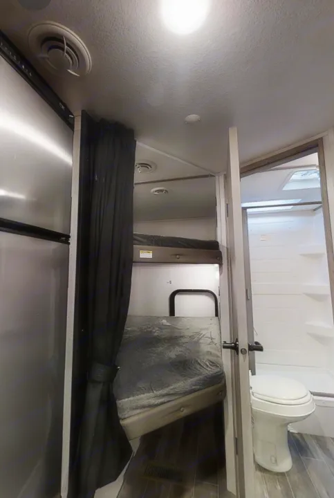 This RV rental interior features compact living with bunk beds, a refrigerator, and a small bathroom with a toilet and shower.. Keystone RV Keystone Passport 2021
