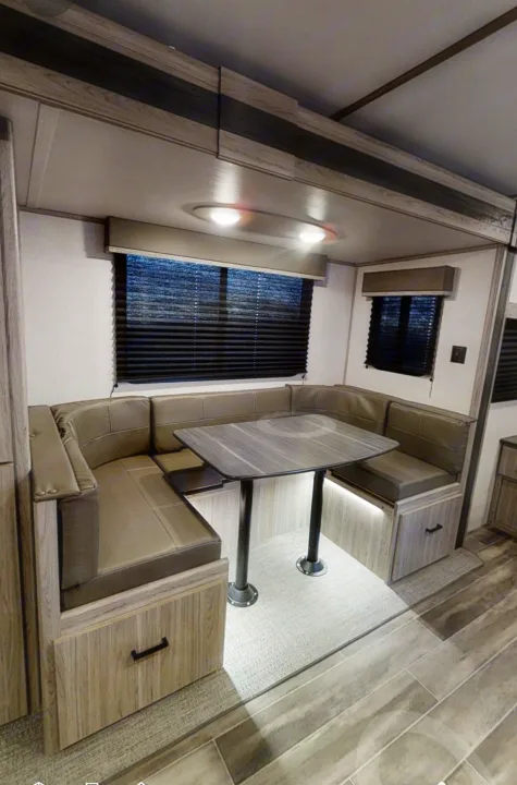 Modern RV rental interior: U-shaped dinette with table, light wood, and comfortable seating for compact living.. Keystone RV Keystone Passport 2021
