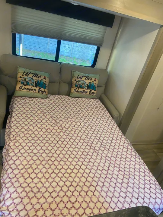 RV rental interior shows a sofa converted to a bed, with themed pillows and window blinds.. Other Tracer 2022