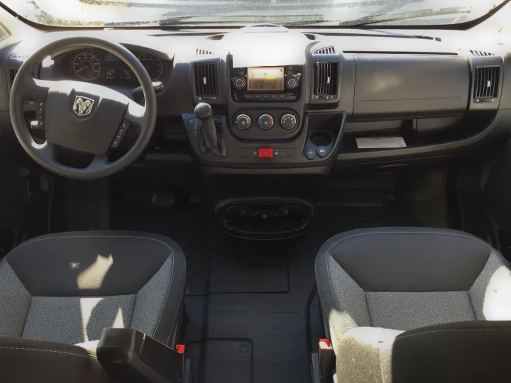 Spacious interior of an RV rental van, featuring the driver's area, dashboard, and front passenger seat.. Winnebago Solis 2022
