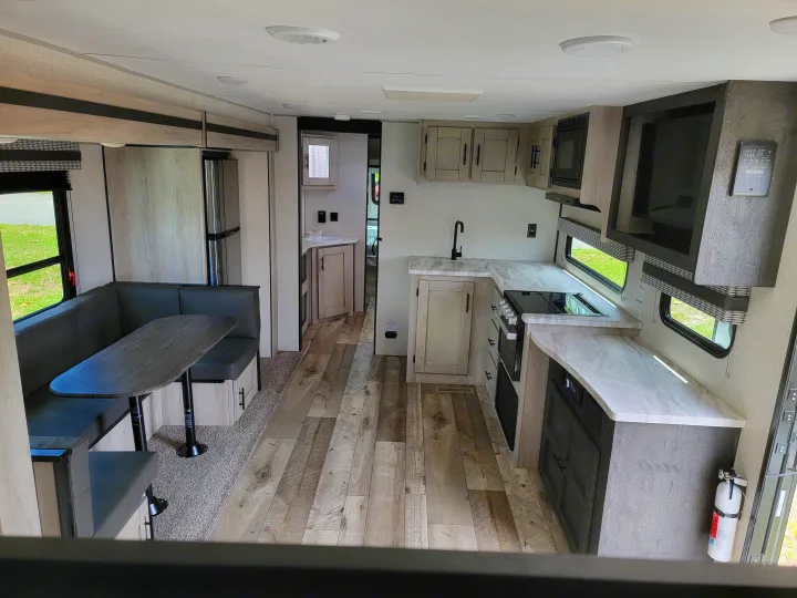 Bright RV rental interior featuring a modern kitchen, comfortable dinette seating, and wood-look flooring throughout.. Otherl Other 2022