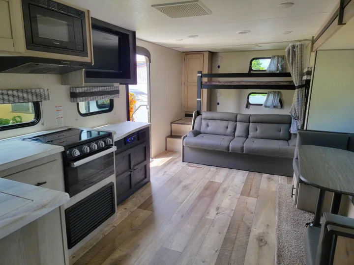 Modern rv rental with a full kitchen (microwave, stove), comfy sofa, bunk beds, & dinette area. Wood-look floors.. Otherl Other 2022