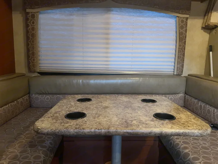 RV rental: interior dinette with patterned bench seating, a table with 4 cup holders, and window blinds.. Thor Chateau 2012