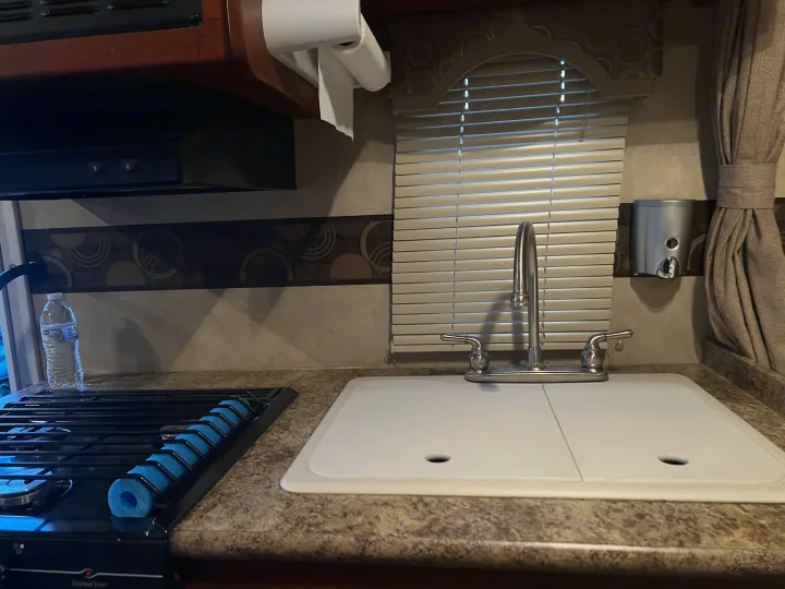 RV rental kitchen: full view of sink, stove, paper towels, and blinds. Compact and functional space.. Thor Chateau 2012