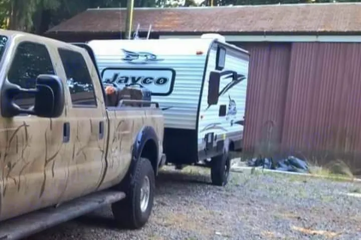 Camo pickup truck towing a white Jayco travel trailer, perfect for an RV rental adventure, parked on gravel.. Jayco Jay Flight 2016