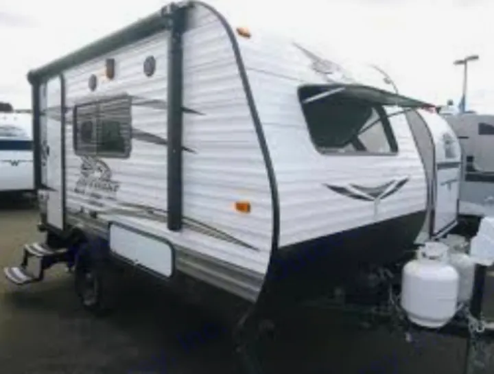 White travel trailer RV rental, featuring a rolled awning, entry steps, and front propane tanks.. Jayco Jay Flight 2016