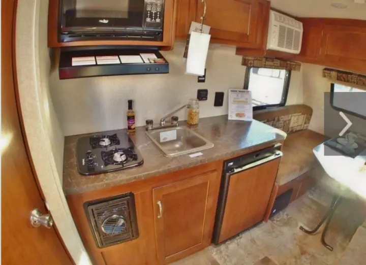 Compact RV rental kitchen features a two-burner stove, sink, microwave, and small refrigerator. Perfect for road trips.. Jayco Jay Flight 2016