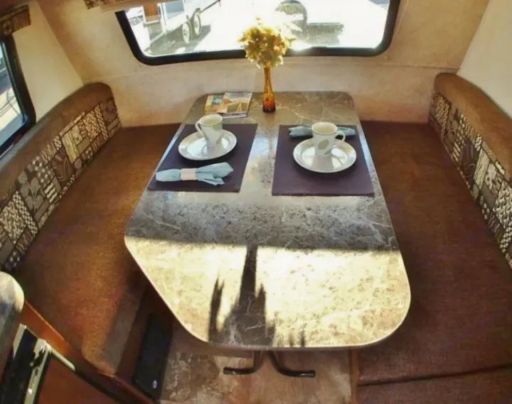 Spacious RV rental interior: dinette area with patterned benches, marled table set for two, bright windows.. Jayco Jay Flight 2016
