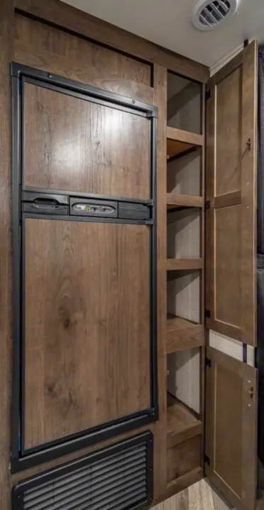 RV rental interior: integrated wood-paneled refrigerator, multi-shelf pantry, and storage cabinets.. Highland Ridge Olympia 26BHS 2022