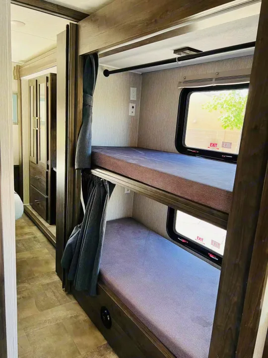 Cozy bunk beds in an RV rental interior, featuring windows, outlets, and privacy curtains, perfect for family trips.. Forest River Coachmen Pursuit 2022