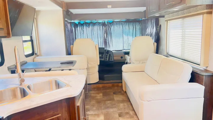 Clean and modern RV rental interior featuring kitchen, dinette, living area, and cockpit with privacy curtains.. Forest River Coachmen Pursuit 2022