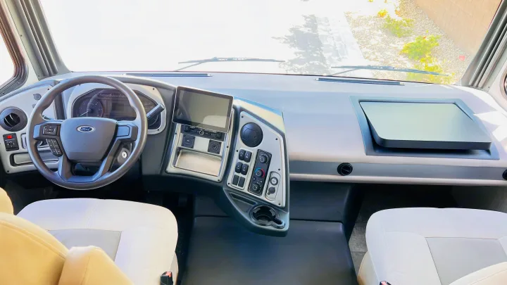 RV rental cockpit: Bright view of a modern dashboard, Ford steering wheel, and comfortable front seats.. Forest River Coachmen Pursuit 2022