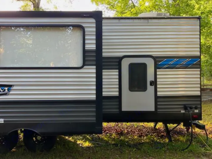 Side view of a modern RV rental travel trailer with a large window and door, ready for your outdoor adventures.. Forest River Salem 2021