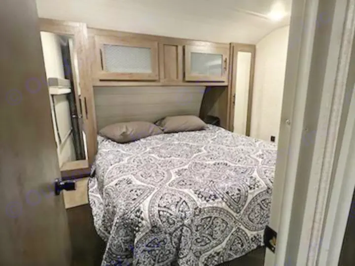 This cozy bedroom in an RV rental features a stylish patterned bedspread and overhead storage.. Forest River Salem 2021