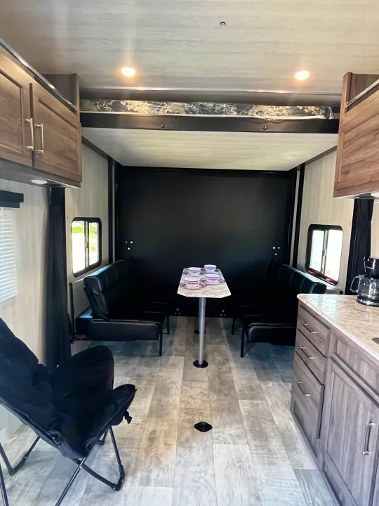 RV rental interior with a versatile living space, featuring a dining area, sofas, and a bunk bed.. Pacific Coachworks Blaze'N 2022
