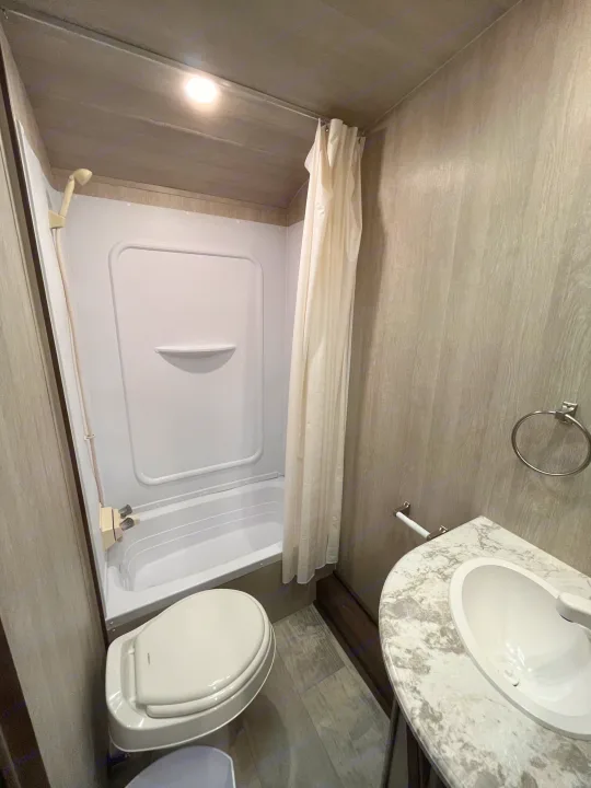 Step inside this RV rental's well-equipped compact bathroom, featuring a shower, toilet, and sink.. Pacific Coachworks Blaze'N 2022