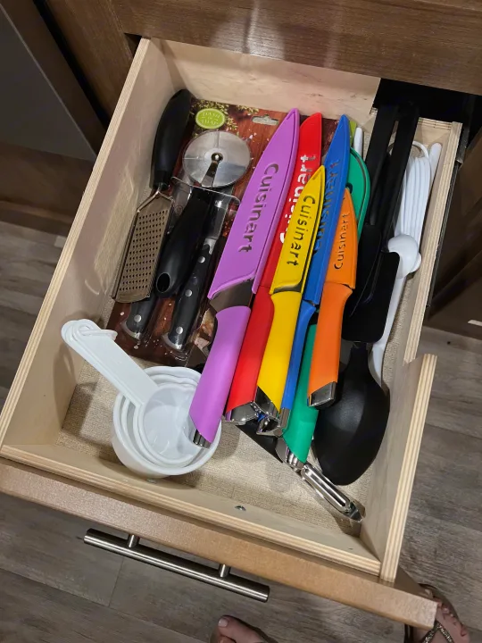 RV rental kitchen drawer full of colorful Cuisinart knives, measuring cups, grater, pizza cutter, and serving tools.. Aspen Trail Aspen Trail Trailer 2018