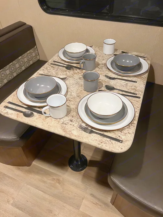 Cozy RV rental dining nook: a table set for four with stylish white and grey dinnerware, complete with black silverware.. Aspen Trail Aspen Trail Trailer 2018