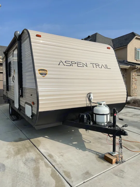 Aspen Trail travel trailer, ideal for an rv rental, parked on a residential driveway, ready for camping adventures.. Aspen Trail LE 2021