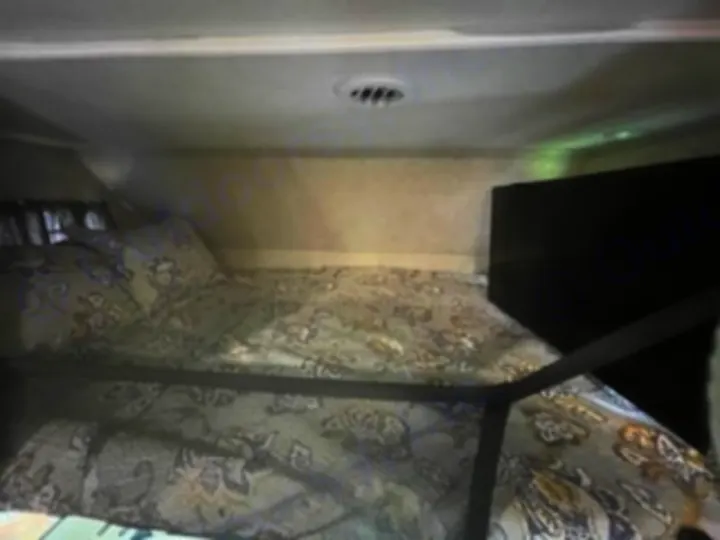 RV rental: Cozy over-cab bunk bed with patterned bedding and safety rail, ideal for compact travel accommodations.. Forest River Sunseeker 2018