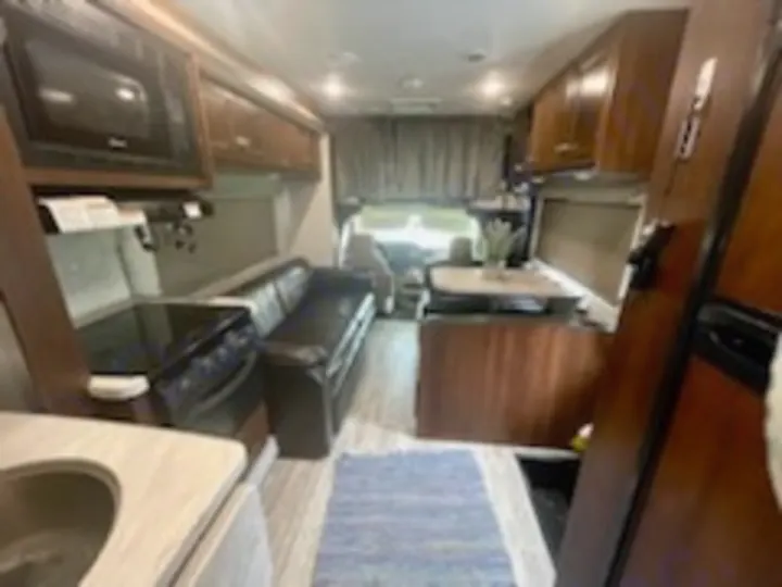 Experience comfortable travel in this modern **RV rental**. Interior shows a compact living space with kitchen, sofa, and dining booth.. Forest River Sunseeker 2018