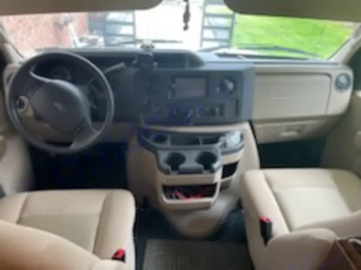 Interior of an RV rental cab, showing the dashboard, steering wheel, and two front seats, ready for your road trip adventure.. Forest River Sunseeker 2018