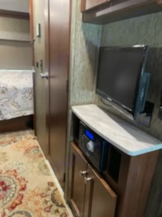RV rental interior: View of the entertainment center with TV & stereo, hallway leading to a bedroom, and patterned carpet.. Forest River Sunseeker 2018