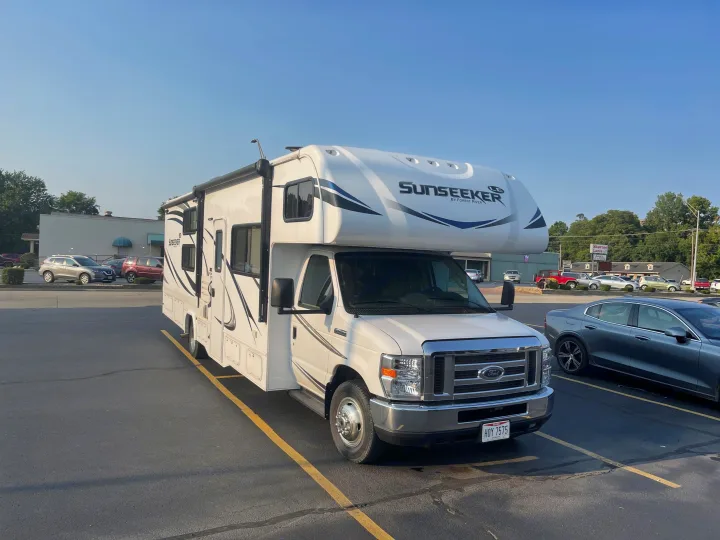 A large white Sunseeker RV rental, featuring an awning and Ohio plate, parked in a sunny lot.. Forest River Sunseeker 2018