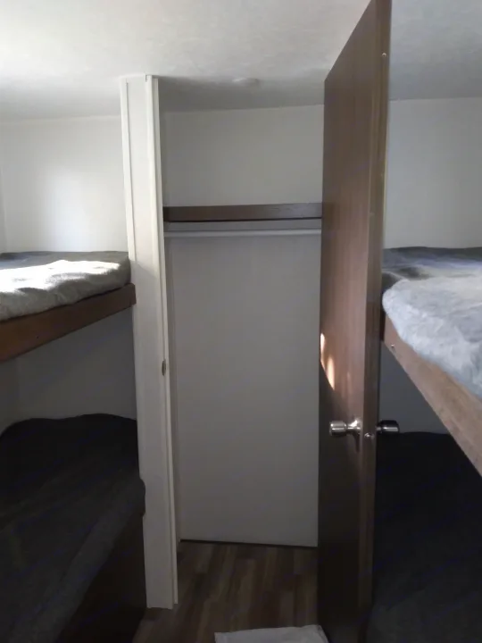 Inside an RV rental: two bunk beds frame a compact closet with a hanging rod, optimizing space for travelers.. Forest River Other 2020