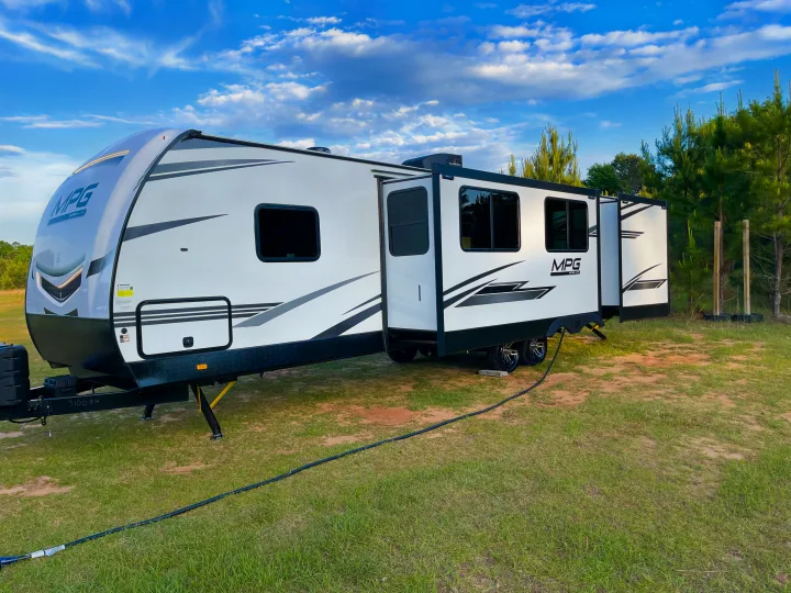 MPG Ultra-Lite travel trailer RV rental, gleaming white, ready for serene outdoor camping under a beautiful blue sky.. Cruiser RV MGP 3100BH 2022