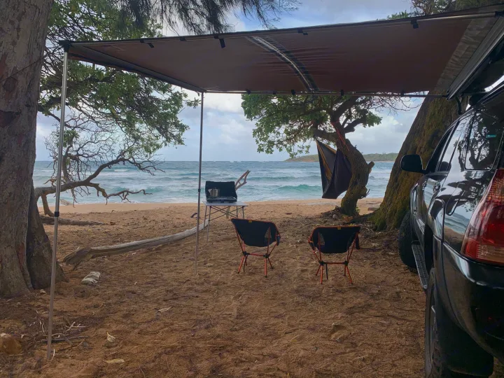 Coastal escape with an RV rental setup: SUV, awning, and camp gear on a sandy beach. Waves crash nearby.. Toyota 4runner 2003