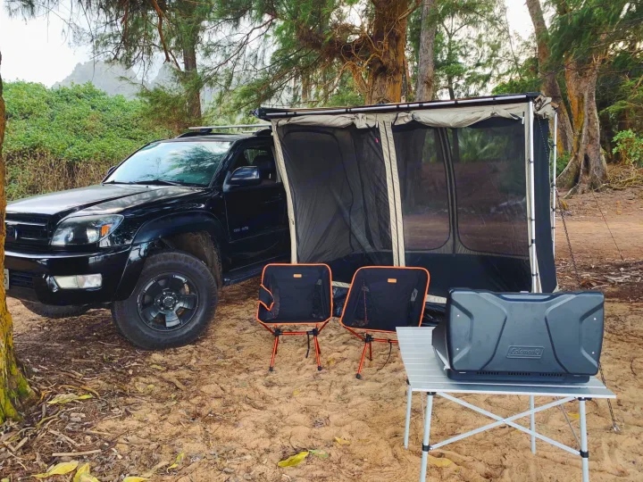Black SUV with attached screen room, chairs, and Coleman stove setup for camping. A unique RV rental alternative for nature trips.. Toyota 4runner 2003