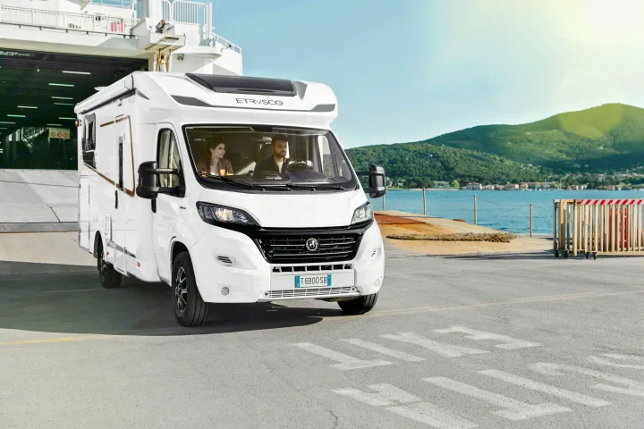 White RV with a couple exits a ferry at a coastal port, suggesting an exciting rv rental road trip adventure.. Etrusco Etrusco T7400SBC 2021
