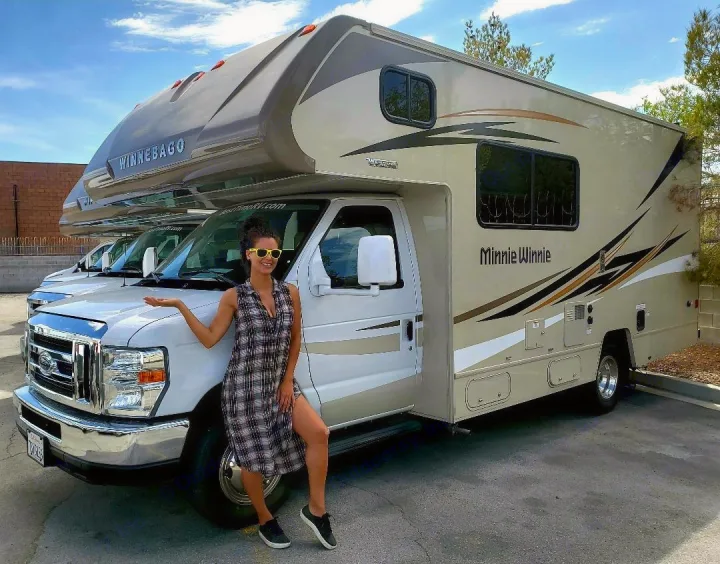 Spacious Winnebago Minnie Winnie RV rental. A smiling woman stands beside this recreational vehicle.. Winnebago Minnie Winnie 2017