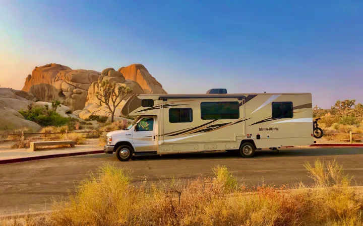 Minnie Winnie RV rental parked in Joshua Tree National Park. A beige motorhome at sunset, surrounded by desert rocks & Joshua trees.. Winnebago Minnie Winnie 2019