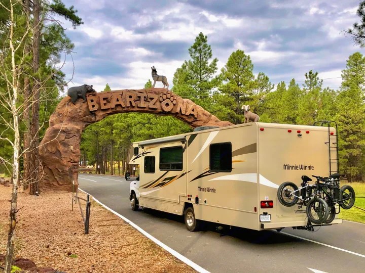 Beige Minnie Winnie RV rental with bikes pauses before the "BEARIZONA" archway entrance featuring animal sculptures.. Winnebago Minnie Winnie 2019
